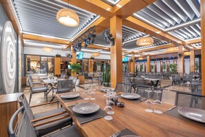 A spacious restaurant with wooden tables and chairs, overhead lighting, and a modern interior design. - Simus Beach Hotel (Manavgat)