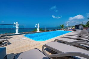 A rooftop pool area with lounge chairs and two white statues. - Simus Beach Hotel (Manavgat)