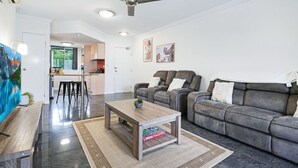 A modern living room with a grey sofa, a wooden coffee table, and a ceiling fan.