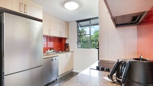 A modern kitchen with stainless steel appliances, wooden cabinets, and a large window providing natural light.