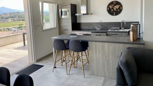 Et moderne køkken med en central ø, barstole, en emfang i rustfrit stål og et verdenskort ur.