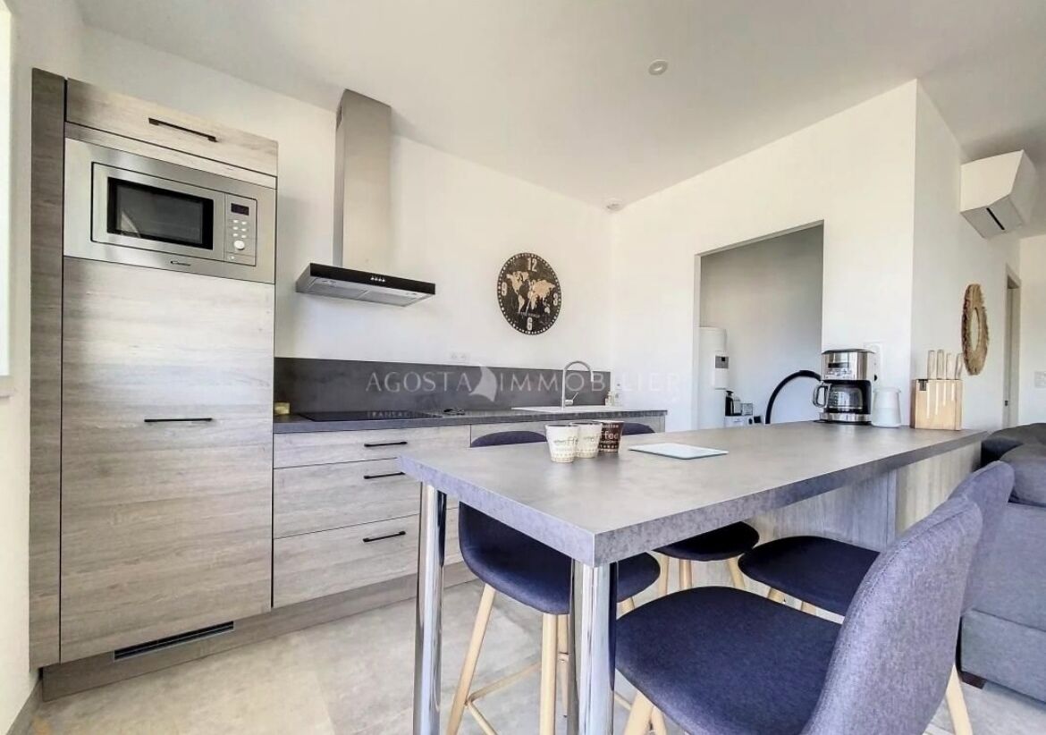 A modern kitchen with a built-in microwave, a stainless steel range hood, and a large island with bar stools.