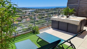 A balcony with a view of the sea, a table with chairs, and a small garden area. - Location vue mer Saint Raphaël (Saint-Raphaël)