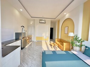 Ein modernes Hotelzimmer mit einem Bett, einer kleinen Sitzecke, einem Essbereich mit Tisch und Stühlen sowie einer Küchenzeile.