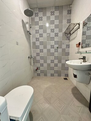 Ein Badezimmer mit gemusterten Fliesen, einer Toilette, einem Waschbecken und einer Dusche.