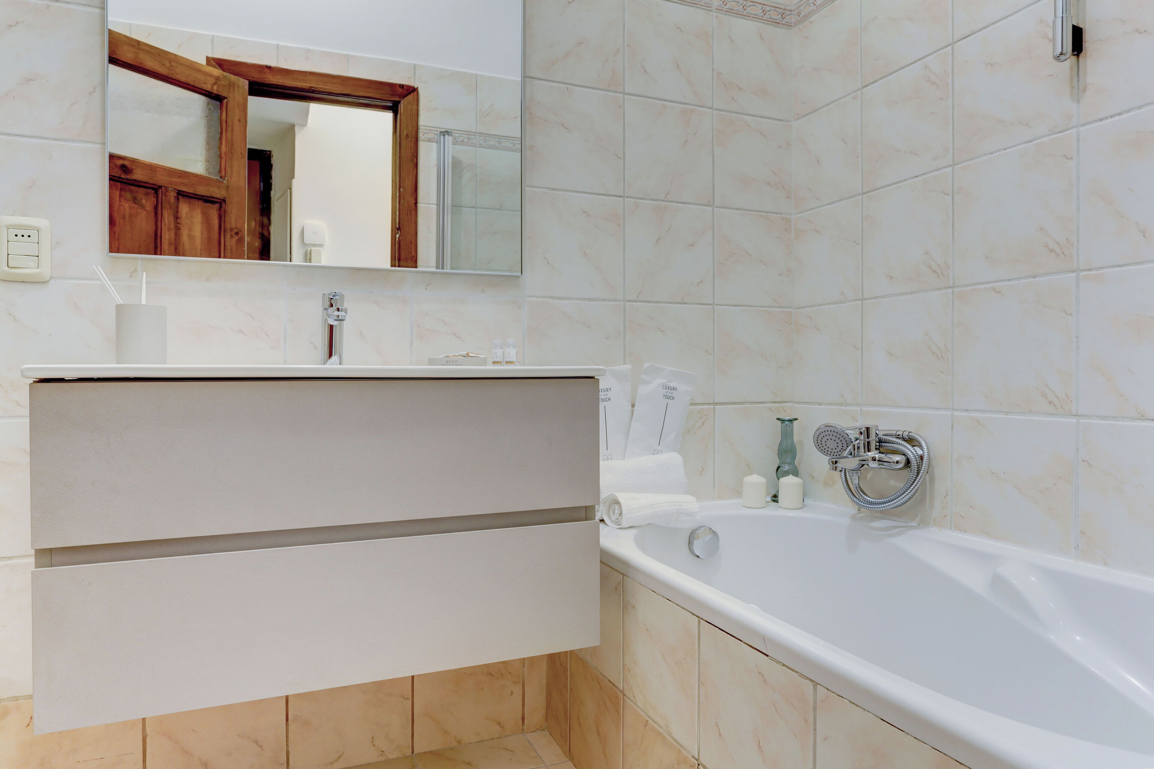 A modern bathroom with a white sink, mirror, and bathtub.