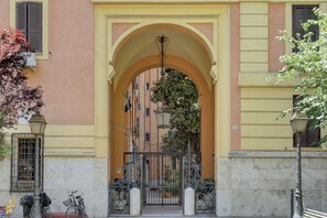 A building entrance with an arched doorway, a gate, and a street lamp. - Vatican Apt Doria 64 (Rome)