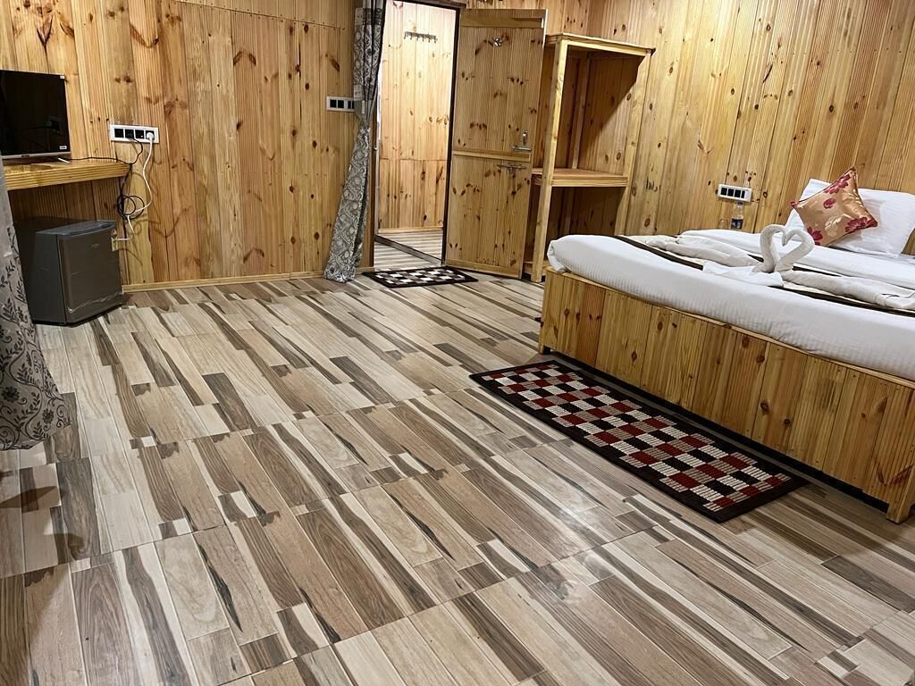 A wooden-paneled room with a bed, a TV, and a small desk.