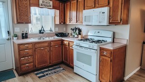 Una cocina con armarios de madera, una estufa blanca, un microondas y un fregadero.