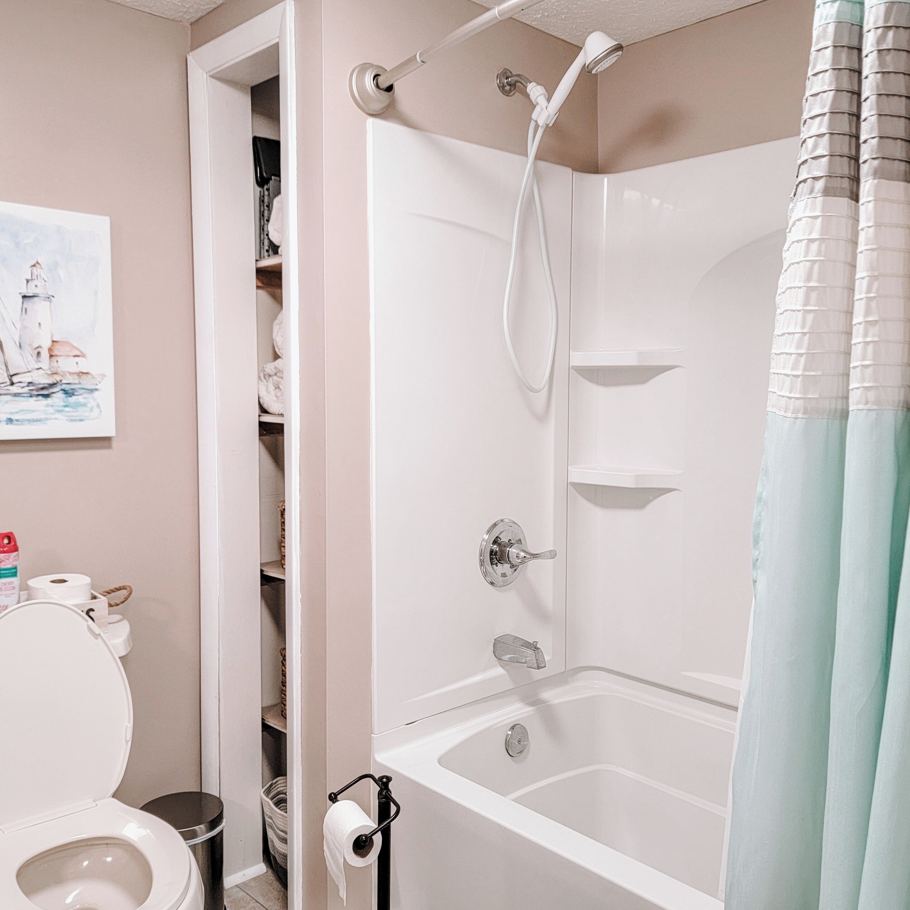 A bathroom with a white bathtub, toilet, and a shelf with toiletries.