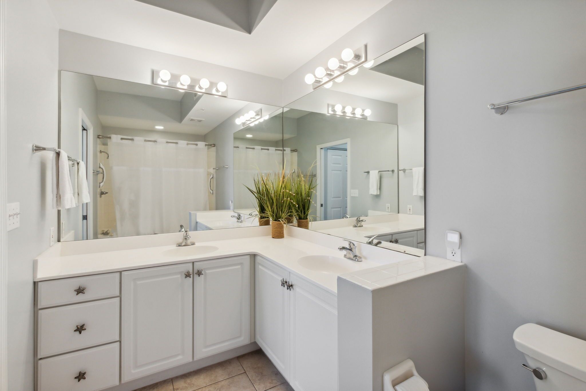 A modern bathroom with a large mirror, vanity, and a toilet.
