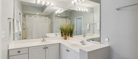 A modern bathroom with a large mirror, vanity, and a toilet.