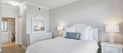 A bedroom with a bed, nightstands, a ceiling fan, and a bathroom visible in the background.
