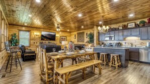 A rustic wooden interior with a dining area, bar seating, and a kitchen with modern appliances. - Mountain Views and City Lights- Convenient to Attractions-Hot Tub Game Tables (Pigeon Forge)