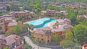 Zona residencial com uma grande piscina cercada por casas em terraço e telhados vermelhos.