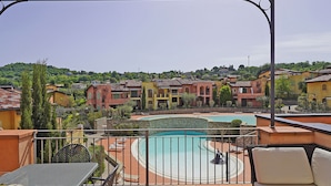 A rooftop terrace with a pool, outdoor seating, and a view of a residential area. - Borgo del Torchio G23 by Wonderful Italy (Manerba del Garda)