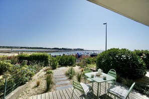 A terrace with a view of the sea, a table and chairs, and a pathway leading to the beach.