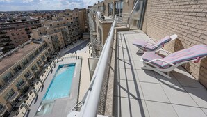 A rooftop pool area with lounge chairs and a view of surrounding buildings.