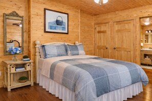 Een slaapkamer met houten lambrisering, een bed, nachtkastje, kaptafel en een lijst met een afbeelding aan de muur.