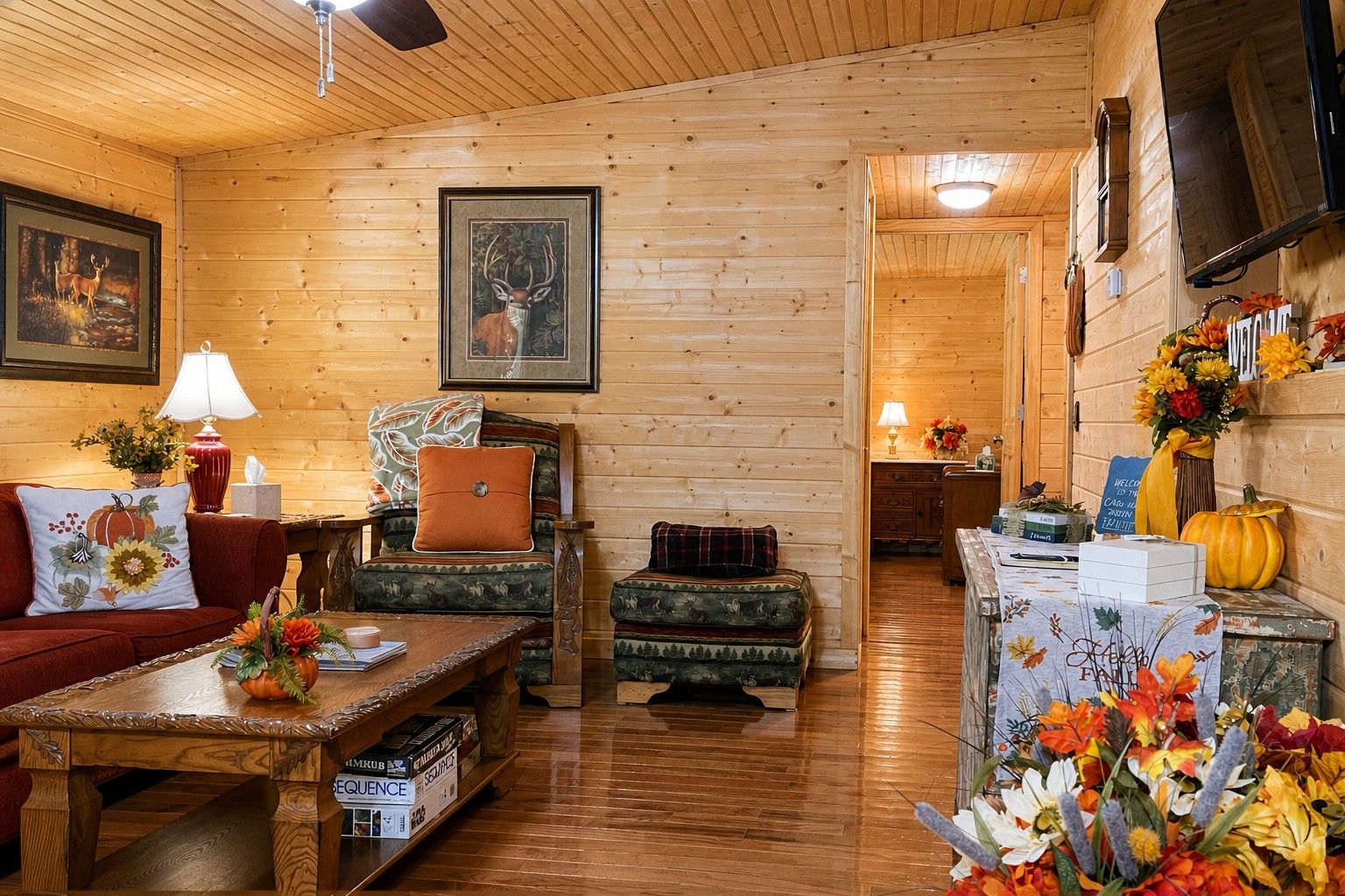 A cozy cabin interior with wooden walls, a sofa, a table with books, and a fireplace.