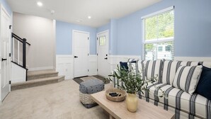 Ein Wohnzimmer mit einer Couch, einem Couchtisch, einer Pflanze und einer Treppe.