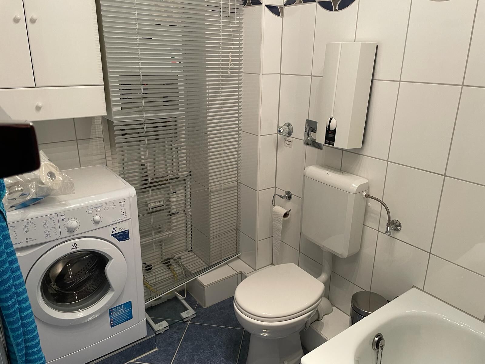 Ein kleines Badezimmer mit Waschmaschine, Toilette und Badewanne.