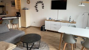 A compact living space with a kitchenette, a dining area, and a seating area with a sofa and a coffee table. - 1 bedroom apartment in grã¶mitz (Grömitz)
