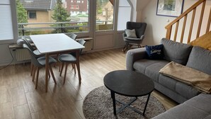A modern living room with a dining table, grey sofa, and a small black table. - 1 bedroom apartment in grã¶mitz (Grömitz)