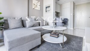 A modern living room with a grey sectional sofa, a round coffee table, and a grey carpet. - Staycae Holiday Homes - ZADA (Dubai)