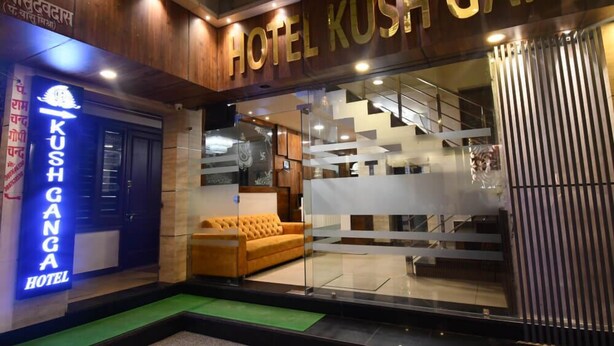 Exterior del Hotel Kush Ganga, con un diseño moderno, que presenta una entrada destacada, una escalera y un sofá visible en el interior.
