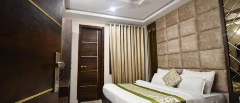 A hotel room with a bed, a wardrobe, a ceiling fan, and a window with curtains.