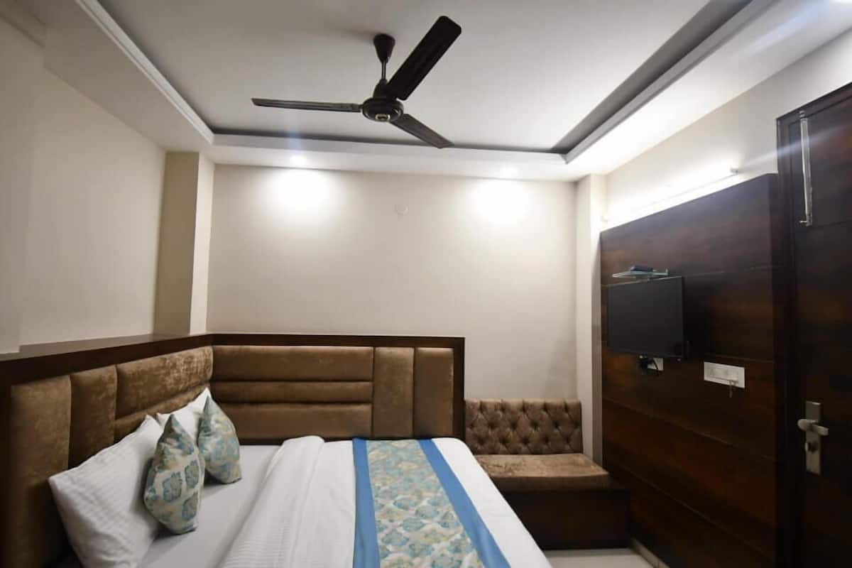 A bedroom with a bed, a ceiling fan, a television, and a wardrobe.