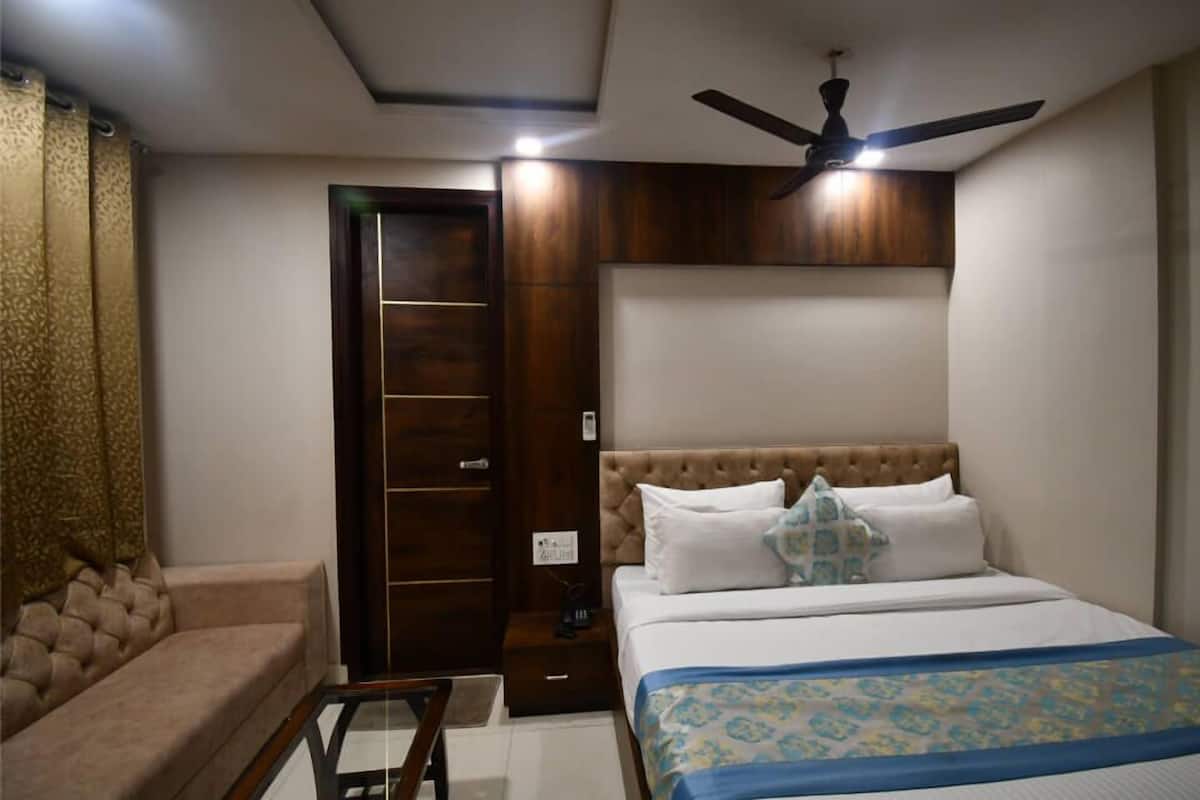 A bedroom with a bed, a ceiling fan, a wardrobe, and a sofa.