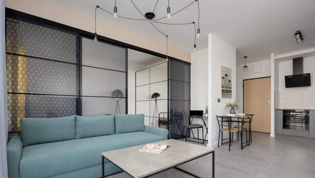 Un salon moderne avec un canapé de couleur turquoise, une table basse et un coin repas comprenant des chaises et une table.