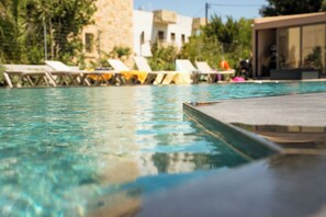 Una piscina con sillones de descanso y un edificio de piedra al fondo.