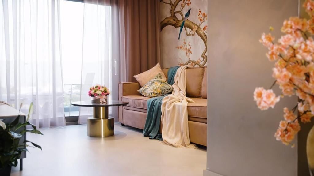 A living room with a sofa, a round coffee table, and a potted plant.