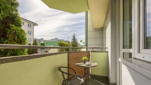 A balcony with a chair, a small table, and a potted plant.