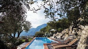Ein Poolbereich mit Liegestühlen und Blick auf Berge.