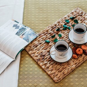 A woven tray with two white cups of coffee and some dried flowers, placed on a textured surface next to an open magazine. - Villa Nova Domus 6 Emma Villas (Gallipoli)