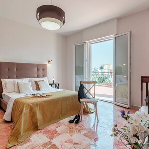 A hotel room with a bed, a chair, a table, and a view of the city through a sliding door. - Villa Nova Domus 6 Emma Villas (Gallipoli)