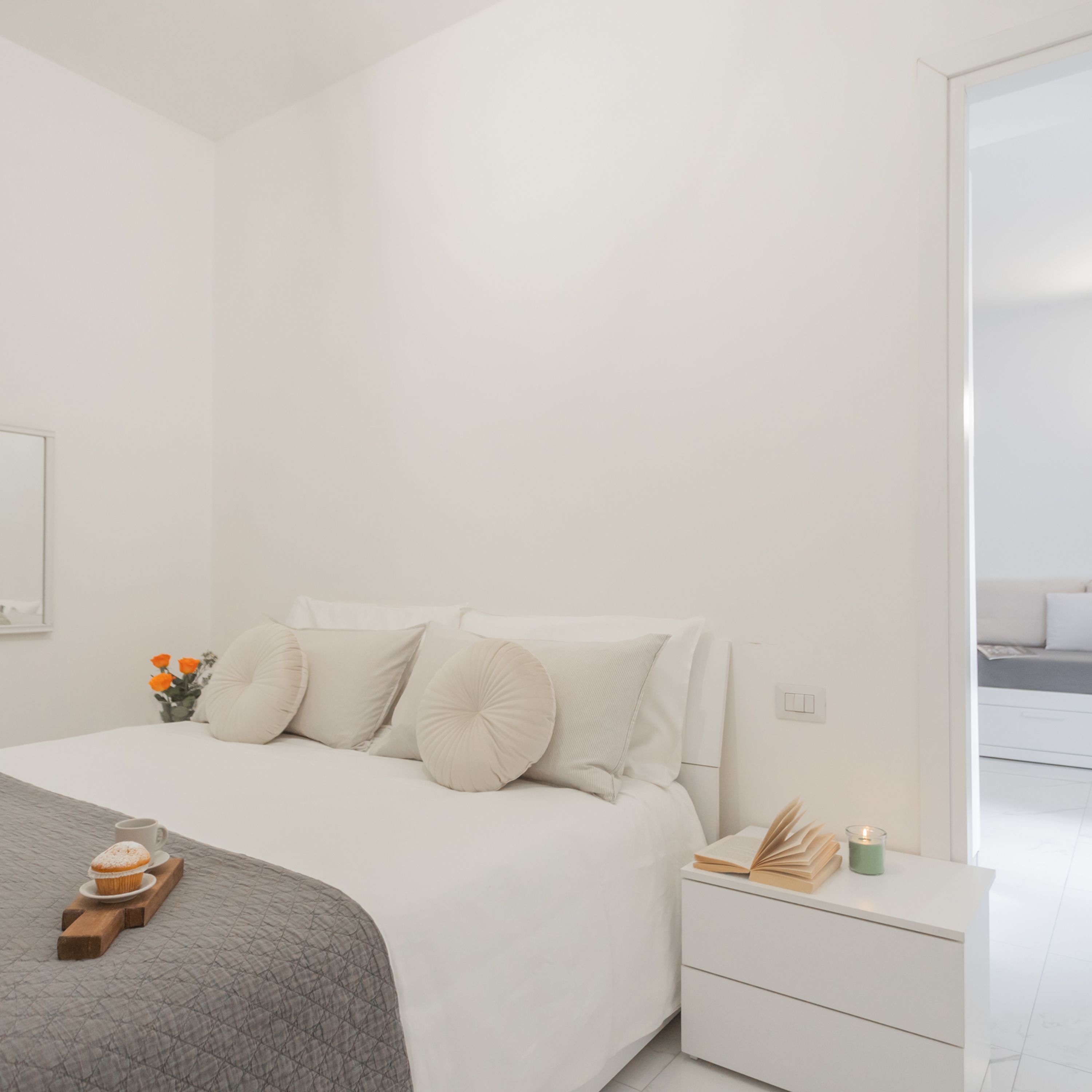 Un dormitorio minimalista con cama, mesita de noche y vistas a un balcón.