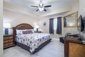 A bedroom with a bed, nightstands, a ceiling fan, a television, and a mirror.