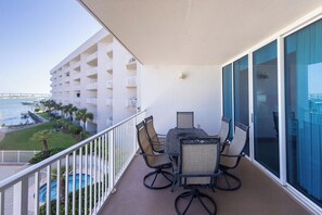 Un balcon avec une table et des chaises, donnant sur une piscine et sur un immeuble doté de balcons.