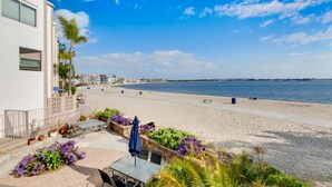 A beachfront property with a patio area, outdoor seating, and a view of the beach and ocean. - Bayfront Oasis Near Boardwalk and Water (San Diego)