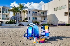 Une plage avec deux chaises de plage et un petit seau jouet.