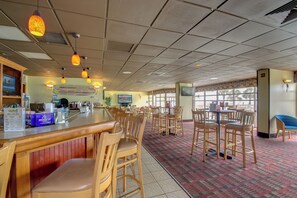 Enjoy dining in this elegant space with wooden tables and chairs, a bar counter, and a large television screen.