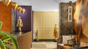 A reception area with a statue, a wall with a geometric pattern, and wicker furniture.