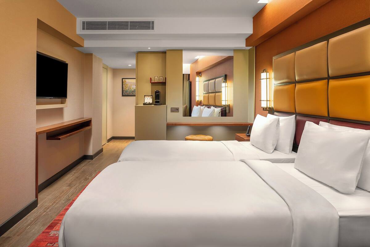 Ein Hotelzimmer mit einem großen Bett, einem Fernseher, einem Spiegel und einem kleinen Tisch.