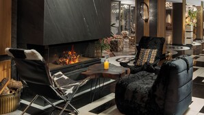 A modern living room with a fireplace, black leather furniture, and a patterned floor.