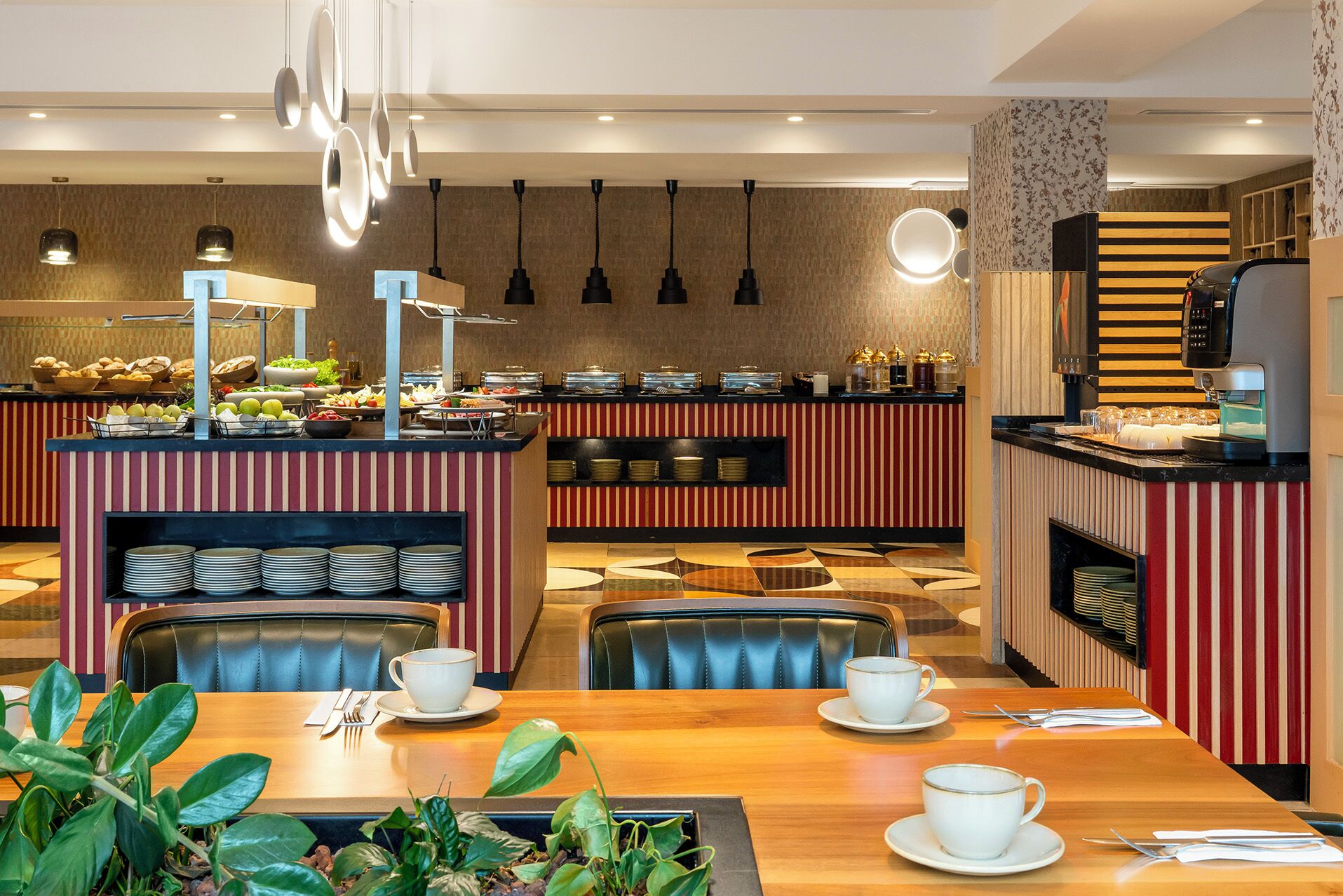 A hotel dining area with buffet counters, seating arrangements, and a coffee machine.
